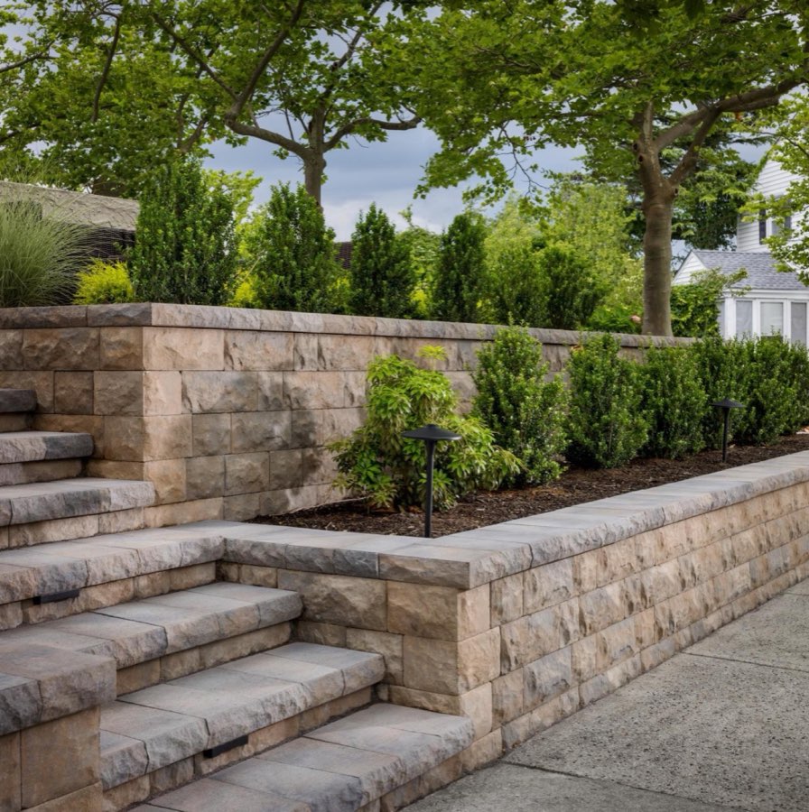 Tiered block retaining wall with stone steps and shrub beds built by GOAT Hardscape in Needham, MA