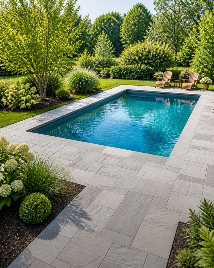 In-ground pool ringed by a bluestone patio and planting beds by GOAT Hardscape in Newton, MA