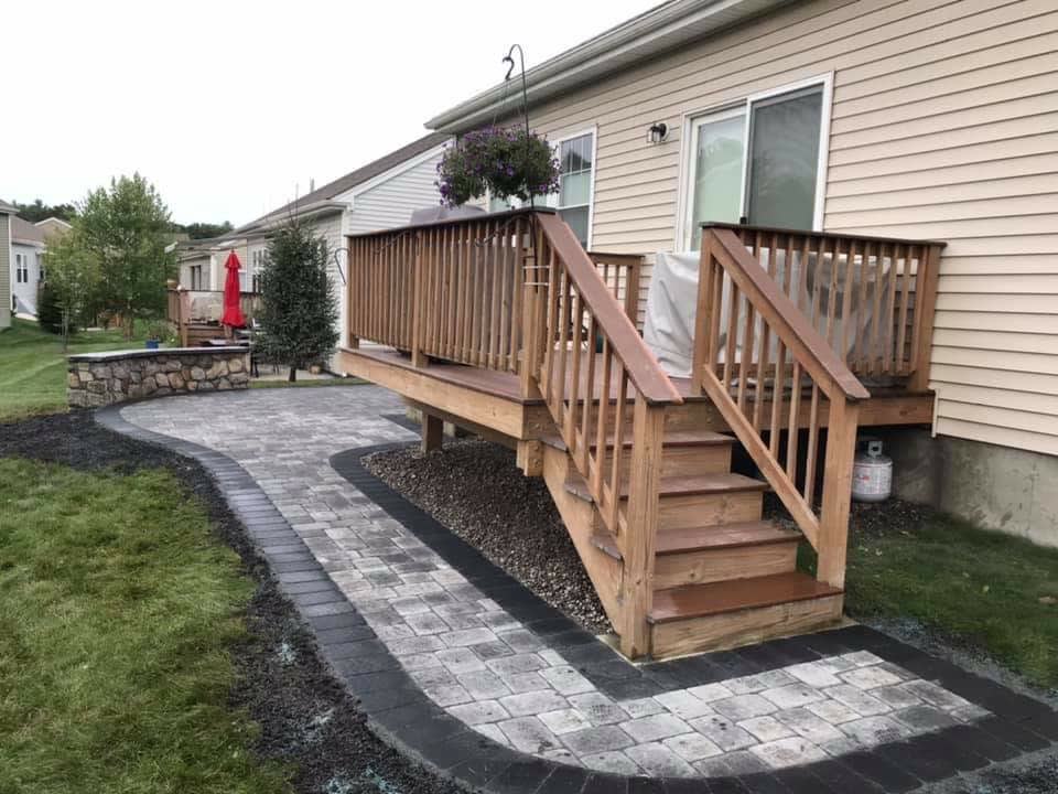 Paver patio and border installed beside a backyard deck